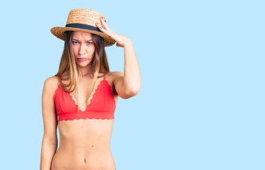 Güzel, esmer, bikini giyen genç bir kadın soru sormayı merak ediyor. Şüpheyle kararsız, kafa kafaya düşünerek. Düşünceli kavram. 