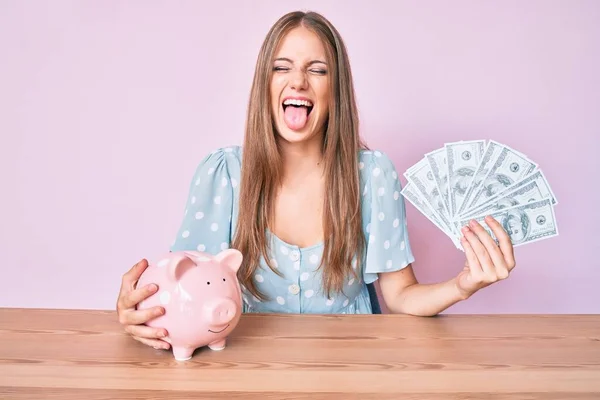 Jong Blond Meisje Holding Dollars Spaarvarken Bank Zitten Tafel Steken — Stockfoto