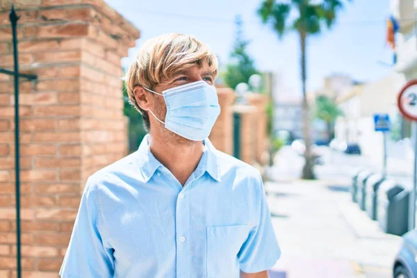 Şehrin caddesinde yürüyen tıbbi maske takan genç İrlandalı adam..