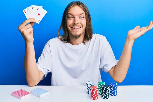 Красивый Белый Мужчина Длинными Волосами Играет Покер Держа Карты Празднования — стоковое фото