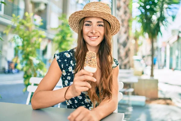 Young hispanic woman on vacation eating ice cream at street of city.