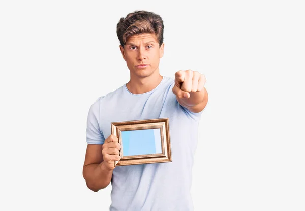 Jovem Homem Bonito Segurando Moldura Vazia Apontando Com Dedo Para — Fotografia de Stock