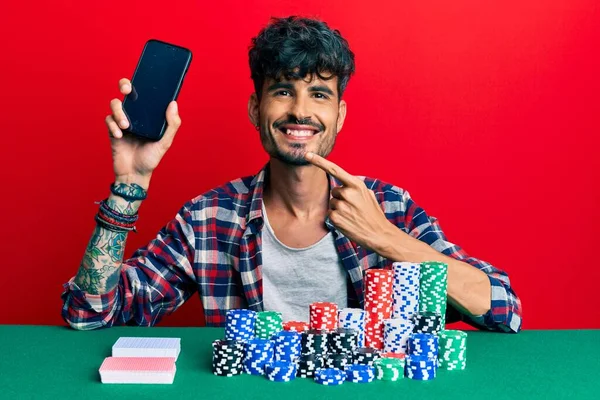 Jovem Hispânico Sentado Mesa Com Fichas Poker Cartões Segurando Smartphone — Fotografia de Stock