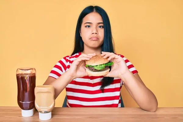 Joven Chica Asiática Comiendo Una Sabrosa Hamburguesa Clásica Deprimida Preocupada —  Fotos de Stock