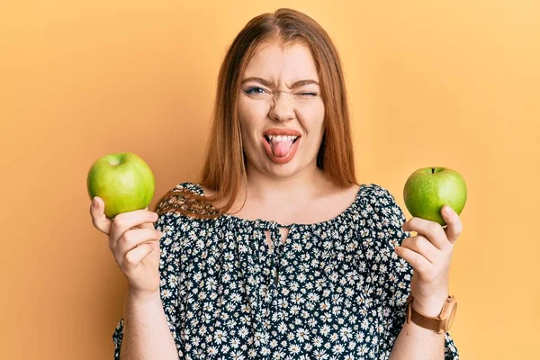 Joven Hermosa Pelirroja Sosteniendo Manzanas Verdes Sacando Lengua Feliz Con —  Fotos de Stock