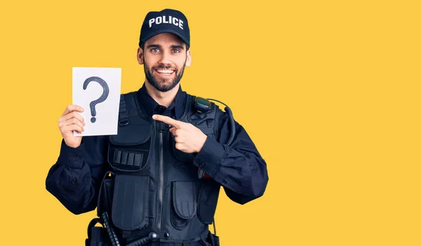 若いですハンサムな男とともに髭を生やして警察制服保持質問マーク笑顔幸せなポインティングとともに手と指 — ストック写真