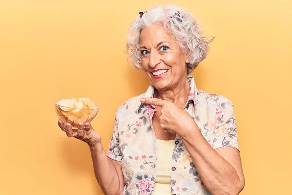 Старша Сіро Волохата Жінка Тримає Картопляний Чіп Посміхаючись Щасливим Вказуючи — стокове фото