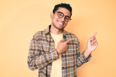 Gündelik kıyafetler giyen, gözlüklü, gülümseyen ve kameraya bakan genç, yakışıklı İspanyol bir adam.. 