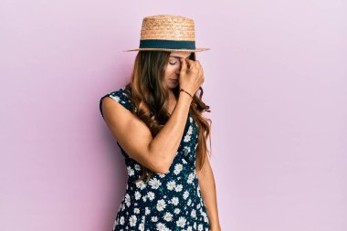 Genç esmer kadın yaz şapkası takıp yorgun burnu ve gözleri ovuşturup yorgun ve baş ağrısı çekiyor. Stres ve hüsran kavramı. 