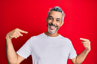 Orta yaşlı, gri saçlı, günlük beyaz tişört giyen, kendine güvenen, gülümseyen, kendini gururlu ve mutlu gösteren bir adam.. 