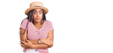 Saçları örülü, yaz şapkası takan, kış soğuğu için titreyen ve soğuktan donan üzgün ve şok olmuş genç Afro-Amerikalı kadın. 