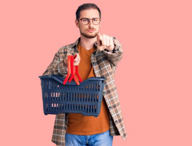 Elinde süpermarket alışveriş sepeti olan yakışıklı beyaz bir adam kamerayı işaret ediyor ve sen kendine güvenen ciddi bir hareket yapıyorsun. 