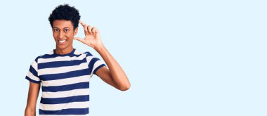 Gündelik kıyafetler giyen, gülümseyen, kendine güvenen, el hareketi yapan, parmaklarıyla işaret yapan ve kameraya bakan genç Afro-Amerikan bir adam. ölçüm kavramı. 