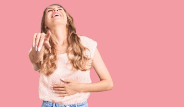 Sarışın, güzel, beyaz bir kadın sana gülüyor, kamerayı işaret ediyor, vücudunu gösteriyor, utanç ifadesi takınıyor. 