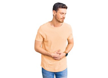 Ayılı yakışıklı genç adam, midesi üstünde sıradan sarı bir tişört giyiyor çünkü hazımsızlık, acı verici bir hastalık ve kendini iyi hissetmiyor. Ağrı kavramı. 