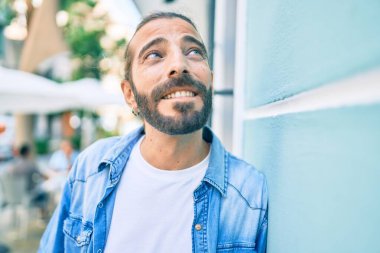 Orta Doğulu genç adam gülümsüyor. Mutlu bir şekilde şehrin duvarına yaslanıyor..