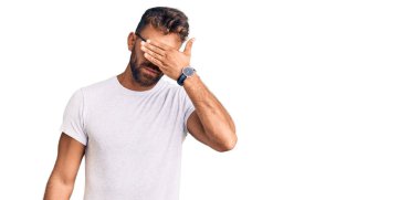 Gündelik kıyafetler giyen ve gözlük takan genç İspanyol bir adam gözlerini eliyle kapatıyor, ciddi ve üzgün görünüyor. Görme, saklama ve reddetme konsepti 