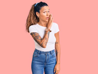 Dövmeli, beyaz tişörtlü, ağzı açık genç bir İspanyol kadın gizli dedikodular söylüyor, kötü niyetli konuşmalar fısıldıyor. 