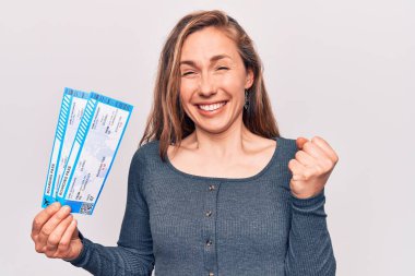 Genç, sarışın bir kadın elinde biniş kartı tutarken gururla bağırıyor, zaferi kutluyor ve başarıyı kollarını kaldırarak kutluyor. 