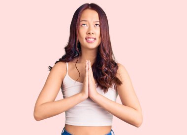 Genç, güzel Çinli bir kız, günlük kıyafetler giyip, elleri bağlı yalvarıyor ve dua ediyor. Yüzünde umut ifadesi var. Çok duygusal ve endişeli. Yalvarıyor. 