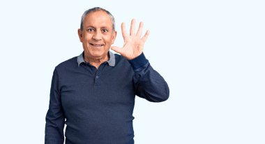 Kıdemli yakışıklı adam gündelik polo giyiyor ve beş numarayı gösterip işaret ederken kendinden emin ve mutlu gülümsüyor.. 