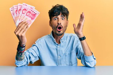 Genç İspanyol adam Yuan Çin banknotlarını elinde tutuyor. Masada korkmuş ve şaşkına dönmüş bir şekilde oturuyor. 