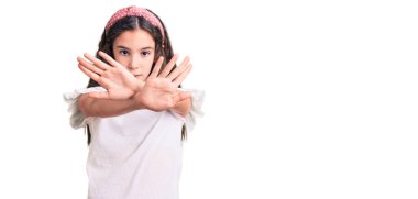 Beyaz tişört giyen tatlı İspanyol kız. Reddedilmiş yüz ifadesi. Kollar ve avuç içleri negatif işaretler yapıyor. 