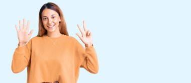 Güzel, genç bir kadın gündelik giysiler giyer ve sekiz numaralı parmaklarıyla işaret ederken kendinden emin ve mutlu gülümserdi.. 