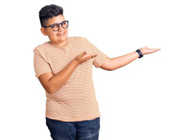 Günlük kıyafetler ve gözlük takan küçük çocuk gülümseyerek içeri girmeye davet ediyor. 