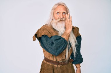 Gri saçlı, uzun sakallı, Viking kostümlü yaşlı bir adam. Ağzına geleneksel bir kostüm giymiş. Gizli dedikodular söylüyor. 
