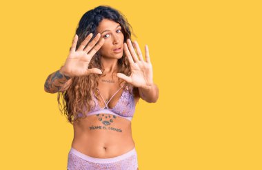 Dövmeli, iç çamaşırlı, el ve parmaklarıyla çerçeve yapan genç İspanyol kadın, kamera bakış açısı. 