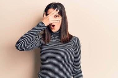 Genç, güzel bir kız, sıradan çizgili tişört giyiyor. Şoka girip yüzünü ve gözlerini eliyle kapatıyor. Parmaklarından bakıyor. 