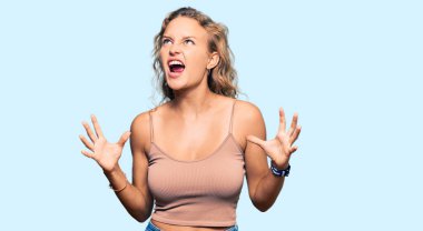 Güzel, beyaz bir kadın, günlük kıyafetler giymiş, deli deli deli bağırıyor, agresif bir ifadeyle bağırıyor ve kollarını kaldırıyor. hüsran kavramı. 