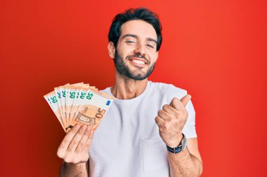 Avro banknotları tutan İspanyol genç adam gururla haykırıyor, zaferi ve başarıyı kutluyor. 