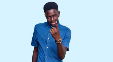 Genç Afro-Amerikalı sıradan kıyafetler giyen bir adam el hareketleriyle bizi buraya çağırıyor. Mutlu ve gülümseyen insanları davet ediyor. 