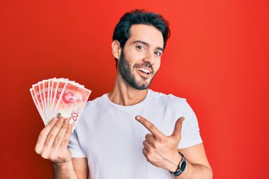 Genç İspanyol adam elinde 20 İsrail şekeri, banknotlar mutlu bir şekilde parmakla işaret ediyor. 