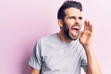 Sakallı, sıradan tişörtlü genç ve yakışıklı bir adam el pençe divan durup bağırıyor. iletişim konsepti. 