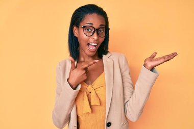 Genç Afro-Amerikan kadın iş kıyafetleri giyip kameraya hayret ediyor ve gülümsüyor.. 