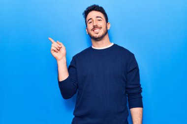 Gündelik kıyafetler giyen genç İspanyol adam gülümsüyor mutlu bir şekilde elini ve parmağını yana uzatıyordu. 