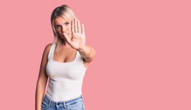 Kolsuz tişört giyen genç, güzel sarışın kadın avucunun içi gibi şarkı söylemeyi kesiyor. Yüzünde olumsuz ve ciddi bir jest olan uyarı ifadesi. 