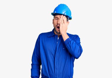 Genç, yakışıklı, işçi üniforması giyen, kasketli, yalvaran ve dua eden bir adam. Yüzünde umut ifadesi olan çok duygusal ve endişeli bir ifade var. Yalvarıyor. 