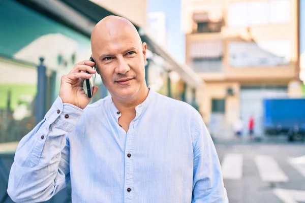 Middle age bald man smiling happy talking on the smartphone at the city.