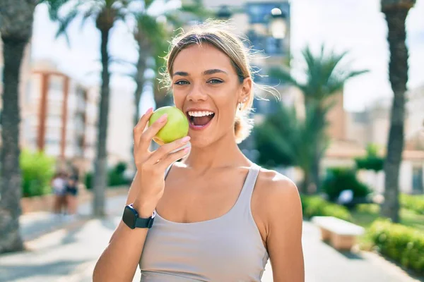 年轻的高加索女子穿着运动服在户外训练 吃着健康的青苹果 — 图库照片