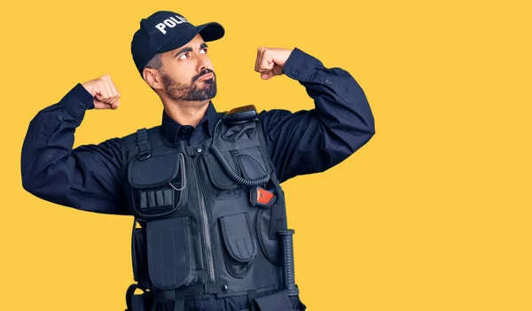 Jovem Hispânico Vestindo Uniforme Policial Mostrando Músculos Dos Braços Sorrindo — Fotografia de Stock