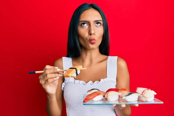 若いブルネットの女性は口と目を細めて魚の顔を作る箸を使用してオムレツ寿司を食べて クレイジーでコミカルな — ストック写真