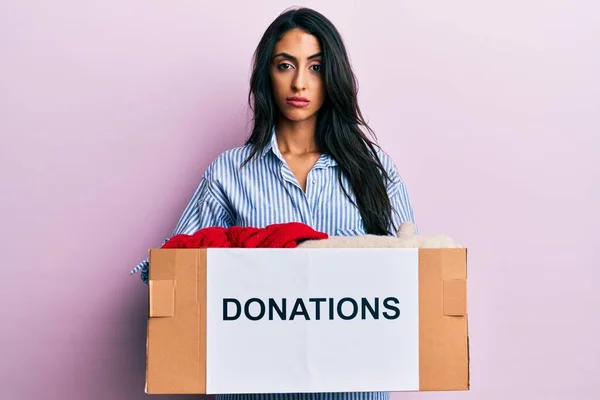 美しいヒスパニック系女性のボランティアの寄付箱を保持懐疑的かつ神経 問題のために動揺を眉をひそめて 否定的な人 — ストック写真