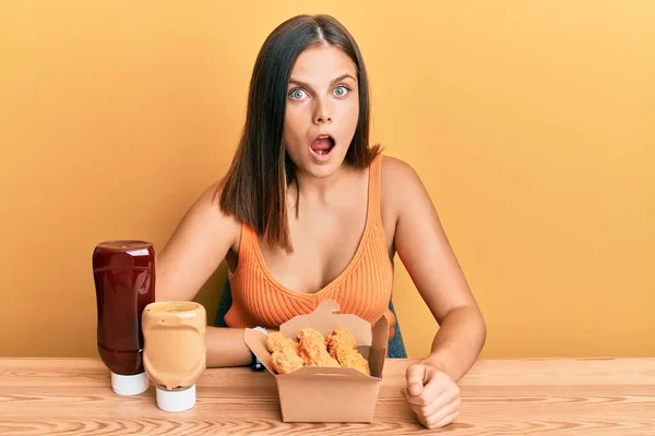 Mujer Joven Caucásica Comiendo Pollo Frito Con Salsas Asustada Sorprendida —  Fotos de Stock