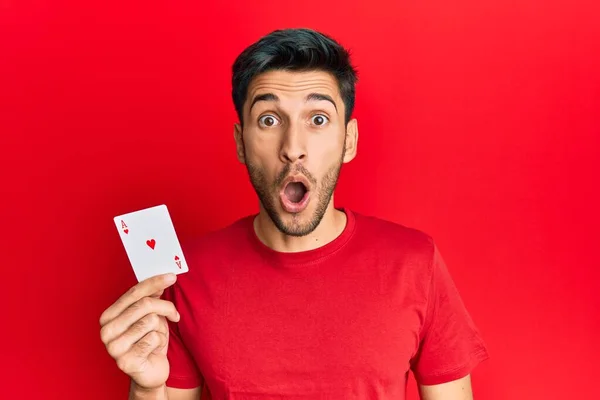 Jovem Homem Bonito Segurando Cartão Poker Ace Assustado Surpreso Com — Fotografia de Stock