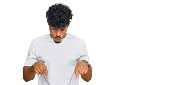 年轻的阿拉伯男子穿着随意的白色T恤 手指垂下 展示广告 惊讶的脸和张开的嘴 — 图库照片