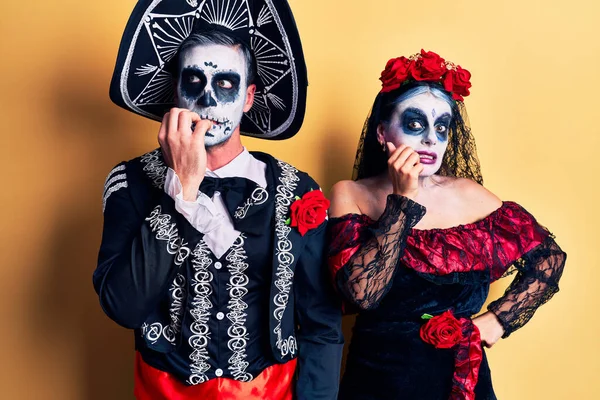 黄色の上に死んだ衣装のメキシコの日を身に着けている若いカップルは 口の爪をかむ上で手で強調し 緊張している 不安の問題 — ストック写真